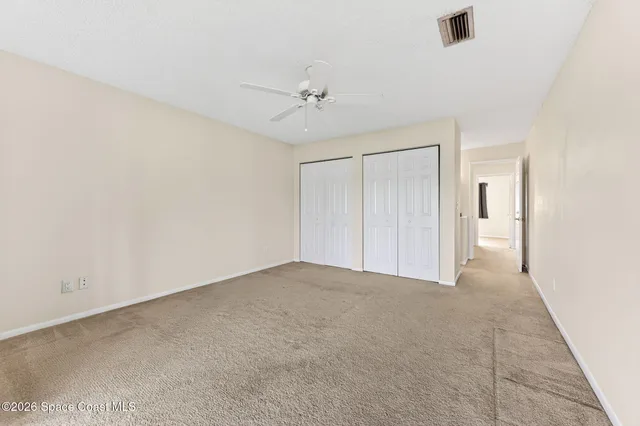 an empty room with windows and ceiling fan view