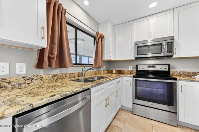 a kitchen with granite countertop a refrigerator stove and sink