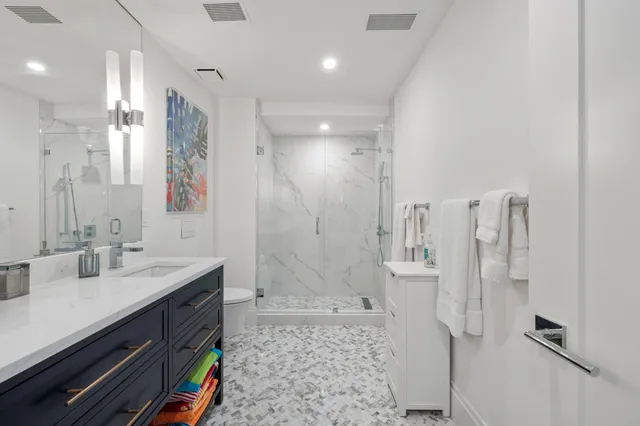 a bathroom with a double vanity sink a toilet a mirror and shower