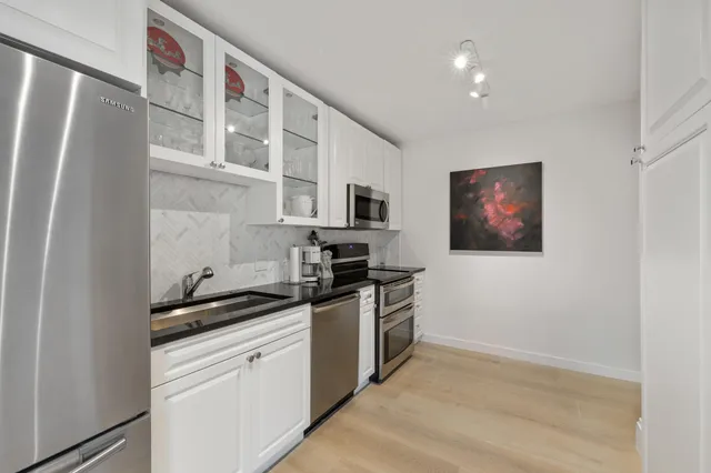 a kitchen with stainless steel appliances granite countertop a refrigerator and a stove top oven