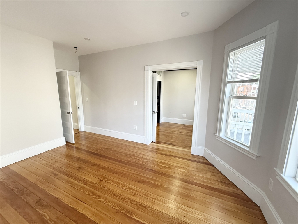 71 Saxton Street, Unit 2 Boston, MA 02125 - Photo 3 of 10 an empty room with wooden floor and windows