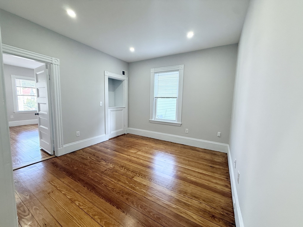 71 Saxton Street, Unit 2 Boston, MA 02125 - Photo 5 of 10 an empty room with wooden floor and windows