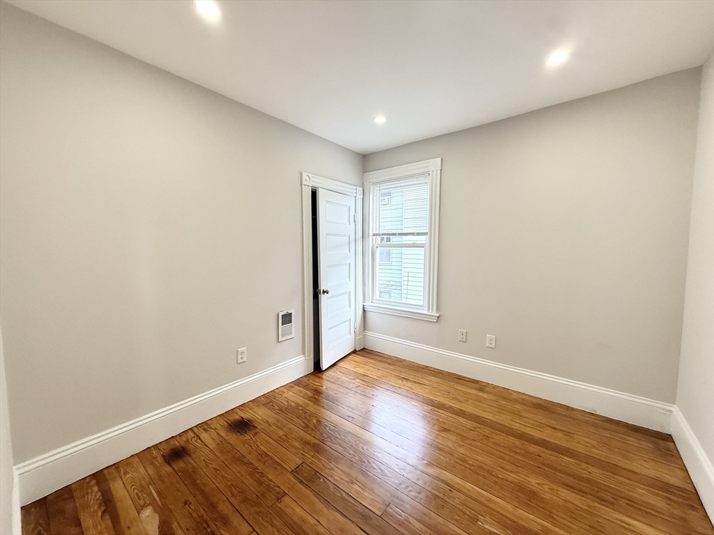 71 Saxton Street, Unit 2 Boston, MA 02125 - Photo 7 of 10 an empty room with wooden floor and windows
