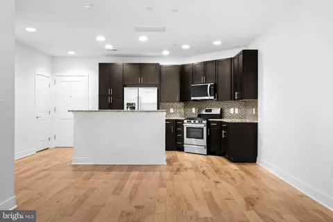 a kitchen with kitchen island stainless steel appliances a refrigerator a stove top oven and a sink