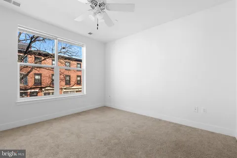 an empty room with windows and fan