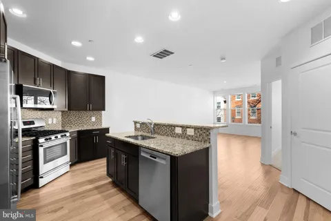 a kitchen with stainless steel appliances granite countertop a stove a sink and a refrigerator