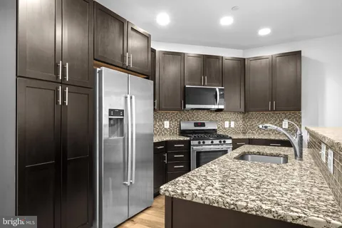 a kitchen with kitchen island granite countertop stainless steel appliances and refrigerator