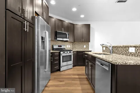 a kitchen with stainless steel appliances granite countertop a refrigerator a stove a sink and a microwave