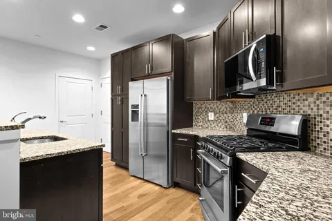 a kitchen with stainless steel appliances granite countertop a sink a stove and a refrigerator
