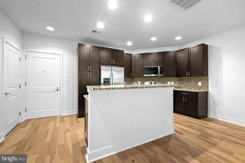 a kitchen with kitchen island granite countertop wooden cabinets and refrigerator
