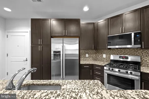 a kitchen with granite countertop a refrigerator and a stove top oven