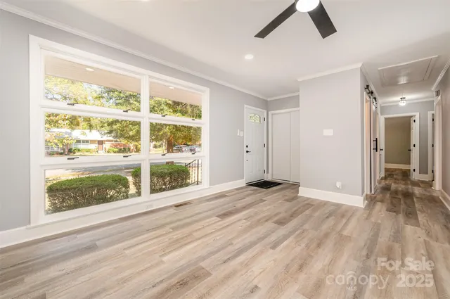 a view of an empty room with wooden floor and a window