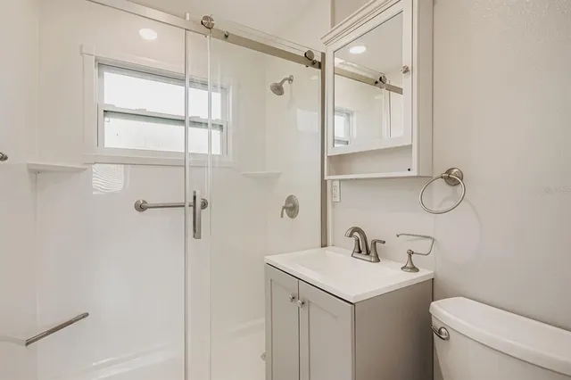 a bathroom with a shower sink vanity and toilet