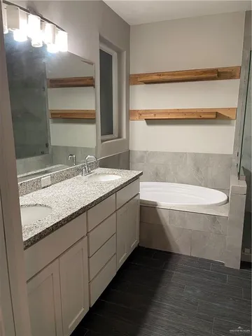 a bathroom with a granite countertop bathtub sink and mirror