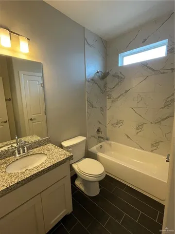 a bathroom with a granite countertop toilet a sink and bathtub
