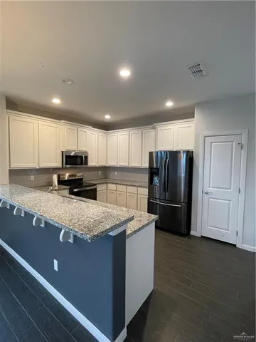 a kitchen with stainless steel appliances granite countertop a refrigerator stove microwave and cabinets