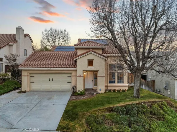 a view of a white house with a large tree and yard