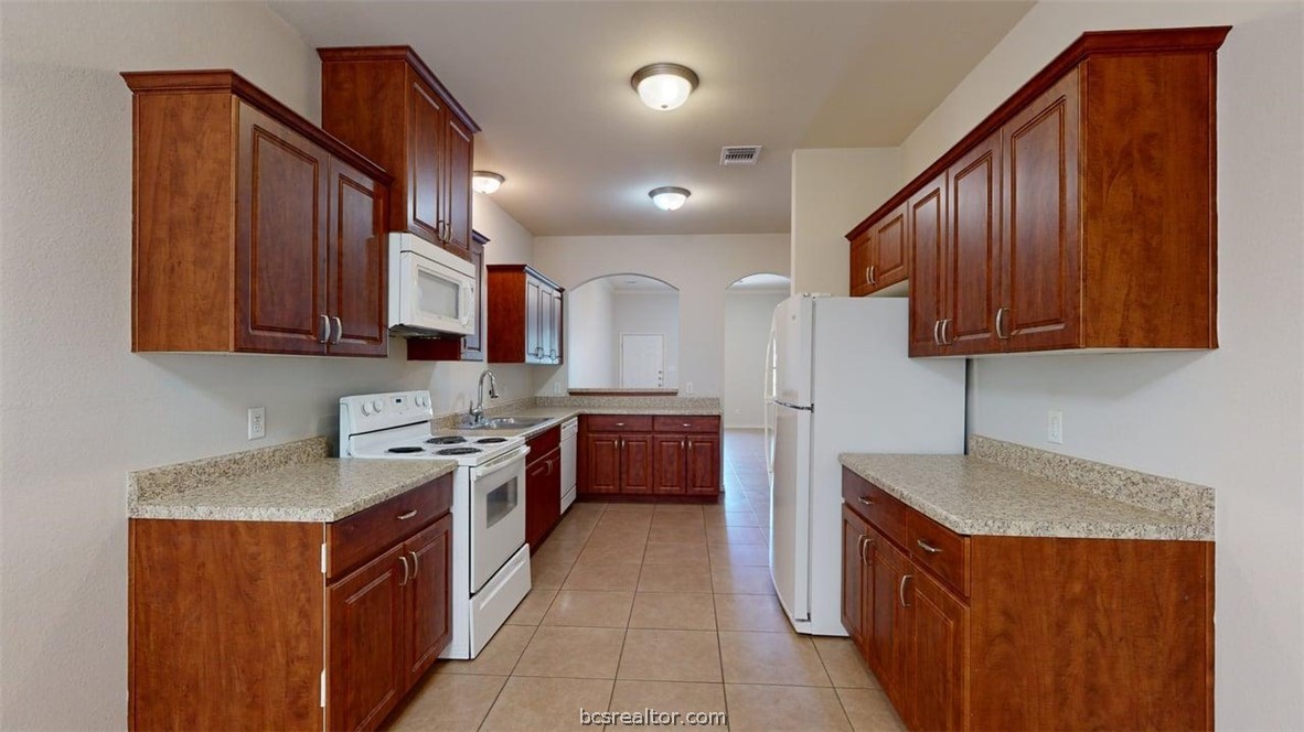 4453-4455 Reveille Road College Station, TX 77845 - Photo 7 of 37 a kitchen with stainless steel appliances granite countertop wooden cabinets a stove a sink and a refrigerator