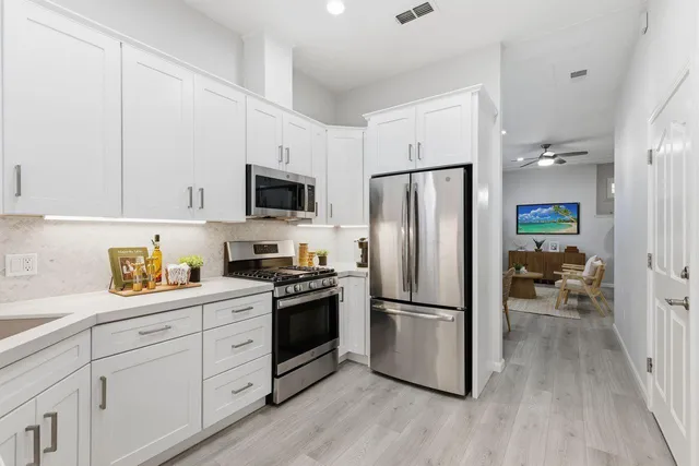 a kitchen with white cabinets stainless steel appliances and a potted plant