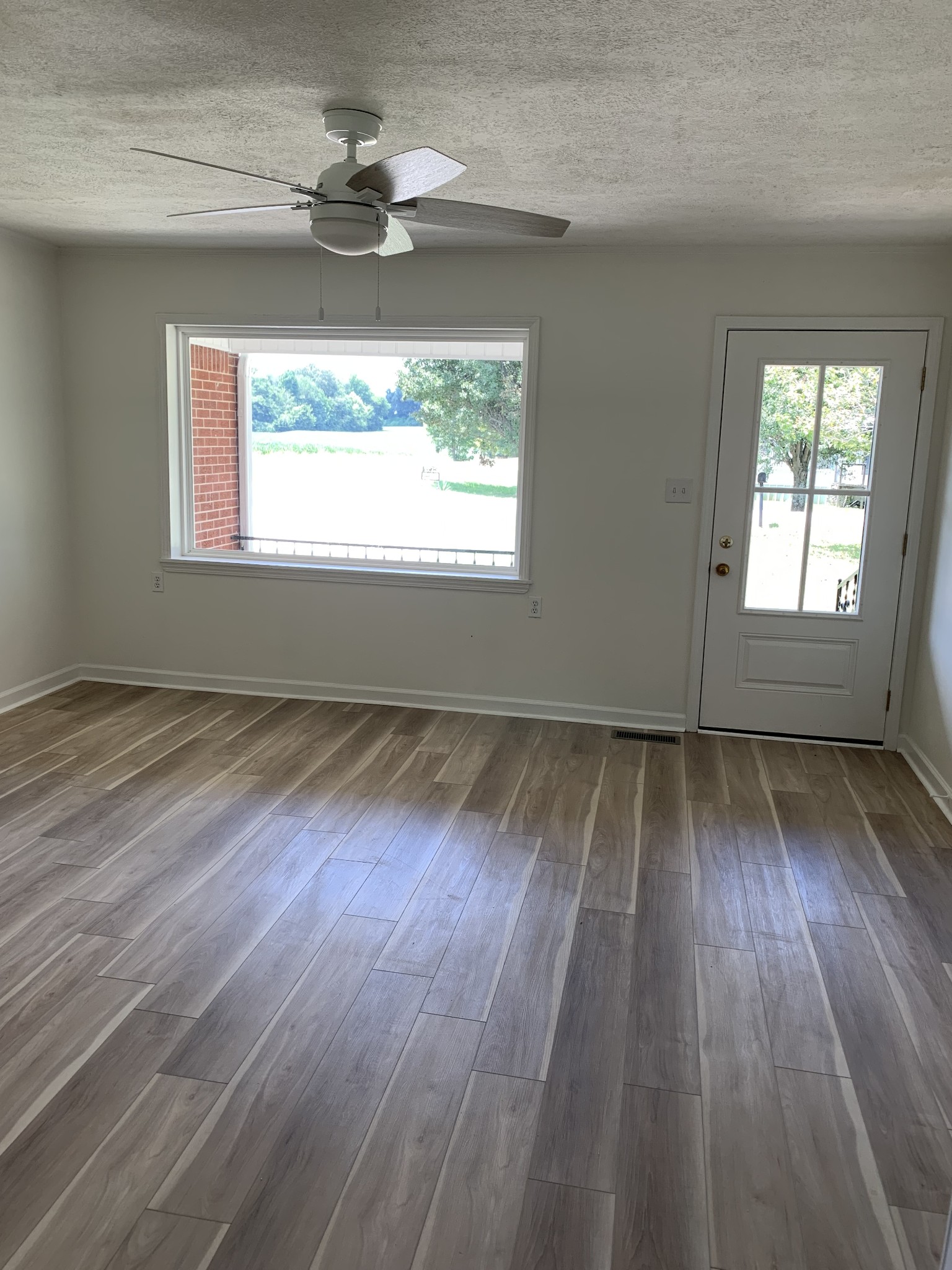 5870 Chestnut Bluff Road Friendship, TN 38034 - Photo 11 of 19 an empty room with wooden floor chandelier fan and windows