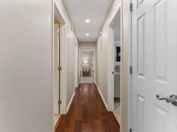 a view of a hallway with wooden floor and a bathroom