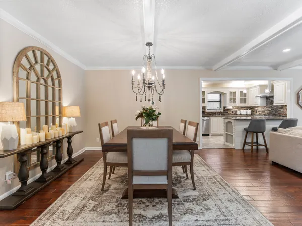 a dining room with wooden floor a chandelier a wooden table and chairs