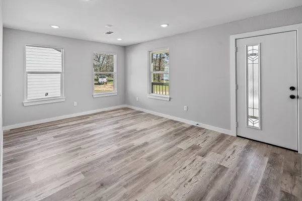 an empty room with wooden floor and windows
