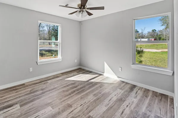 a view of empty room with wooden floor and fan