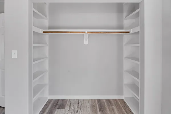 a view of walk in closet with wooden floor