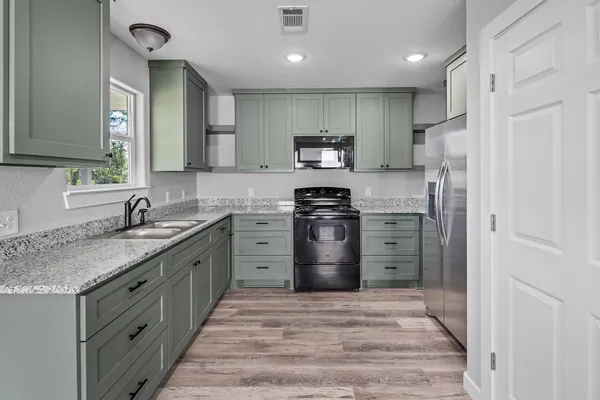 a kitchen with stainless steel appliances granite countertop a refrigerator stove and sink
