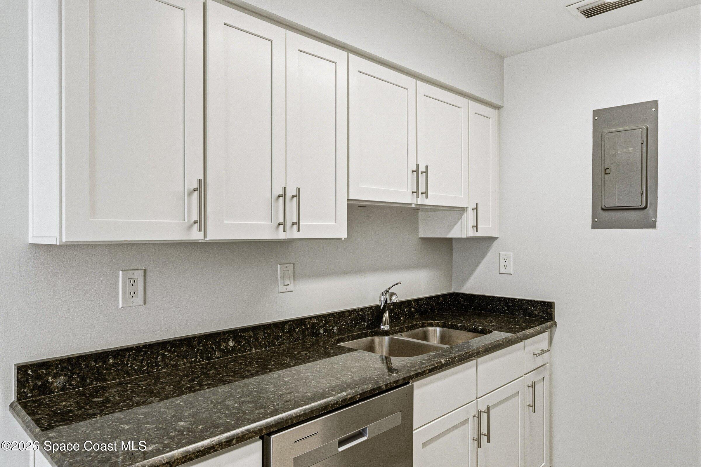 1225 North Wickham Road, Unit 223 Melbourne, FL 32935 - Photo 9 of 26 a kitchen with granite countertop white cabinets and a sink
