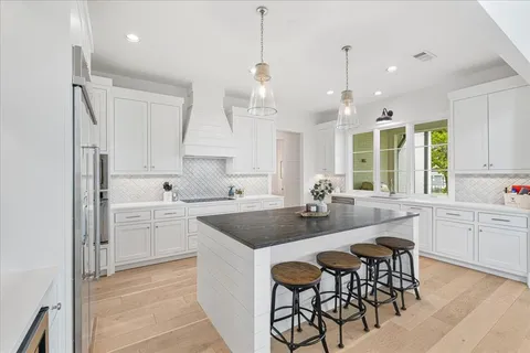 a large kitchen with kitchen island white cabinets and stainless steel appliances