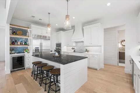 a kitchen with kitchen island granite countertop a sink a counter top space stainless steel appliances and cabinets