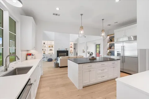 a kitchen with stainless steel appliances kitchen island granite countertop a sink and dishwasher a refrigerator a sink with wooden floor