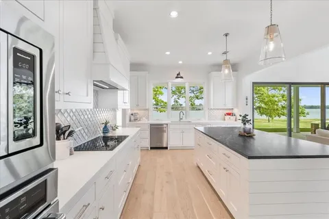 a large kitchen with kitchen island a large window a sink and stainless steel appliances