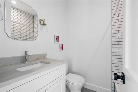 a bathroom with a granite countertop toilet and a sink