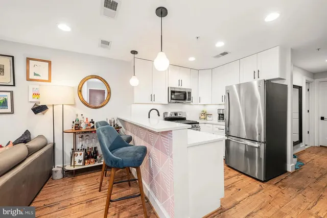a kitchen with stainless steel appliances granite countertop a refrigerator a stove a sink dishwasher a dining table and chairs with wooden floor