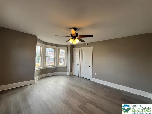a view of an empty room with window and wooden floor