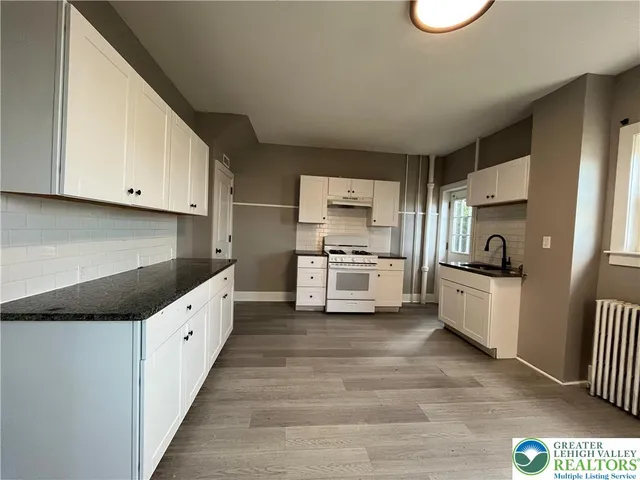 a kitchen with granite countertop white cabinets and white appliances