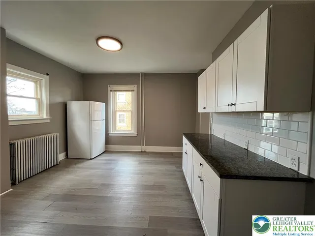 a kitchen with granite countertop white cabinets and window