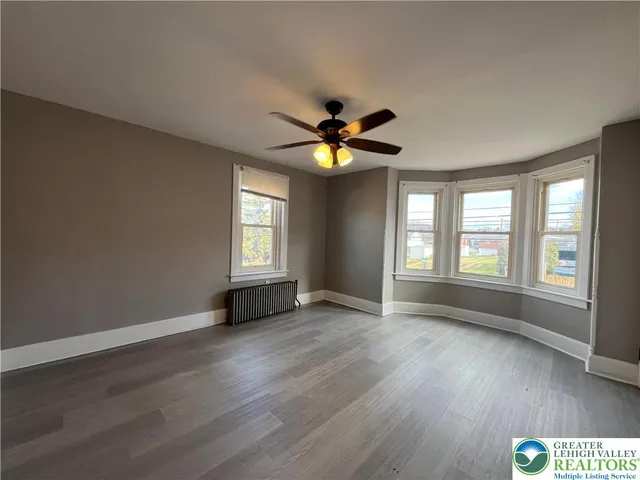 a view of an empty room with a window and wooden floor