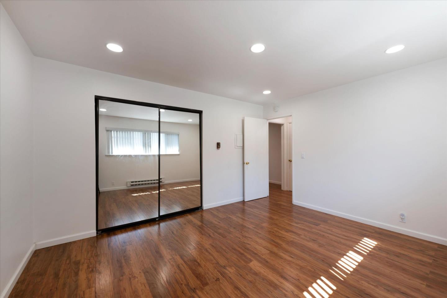 2025 California Street, Unit 42 Mountain View, CA 94040 - Photo 12 of 16 an empty room with wooden floor and mirror