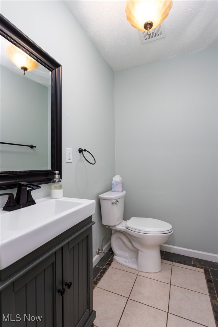14566 West Ridge Road Novelty, OH 44072 - Photo 27 of 49 Half bathroom with toilet, visible vents, baseboards, tile patterned flooring, and vanity
