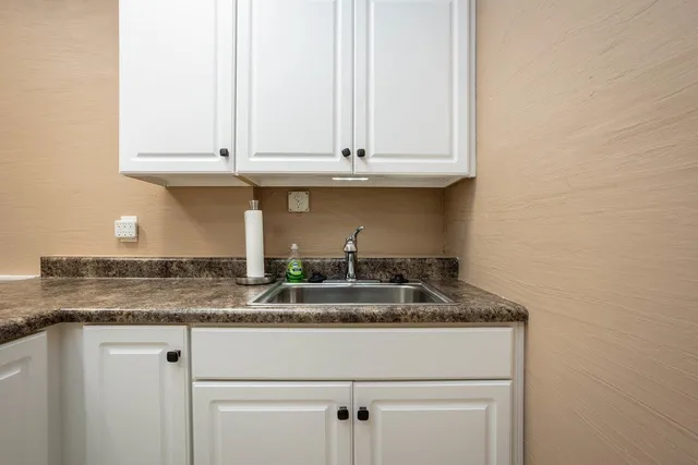a kitchen with granite countertop white cabinets and a sink