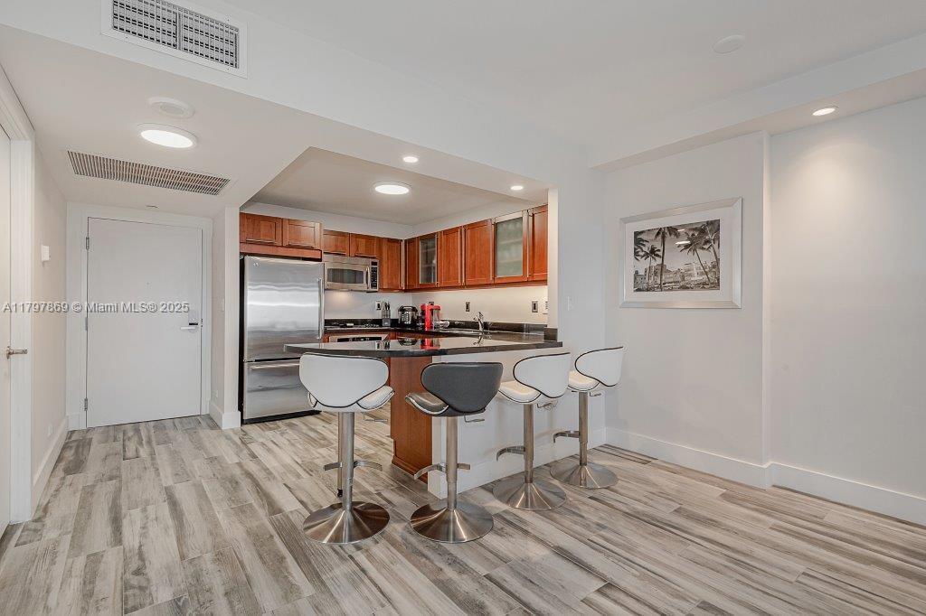 2301 Collins Avenue, Unit 1532 Miami Beach, FL 33139 - Photo 22 of 28 a kitchen with stainless steel appliances kitchen island granite countertop a refrigerator and wooden cabinets
