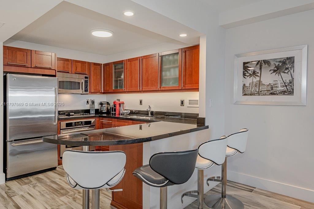 2301 Collins Avenue, Unit 1532 Miami Beach, FL 33139 - Photo 23 of 28 a kitchen with stainless steel appliances granite countertop a sink a stove a refrigerator cabinets and chairs