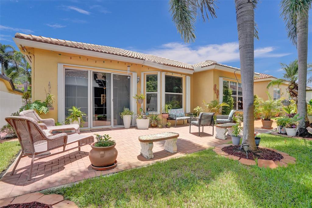 13129 Southwest 32nd Street Miramar, FL 33027 - Photo 31 of 38 a view of a patio with table and chairs potted plants and palm tree