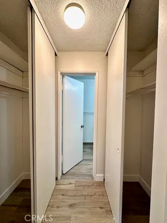 a view of a hallway with wooden floor and closet