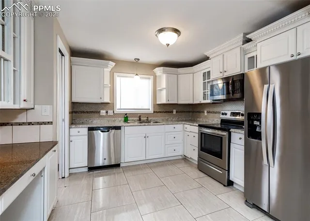 a kitchen with granite countertop a refrigerator sink and cabinets