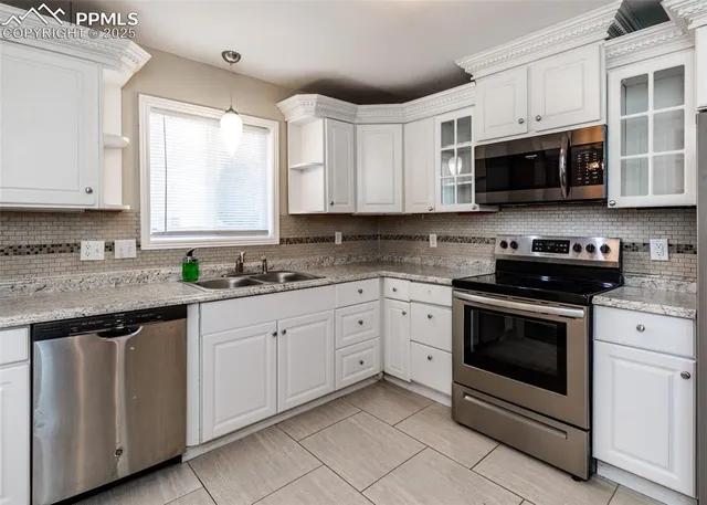 a kitchen with stainless steel appliances granite countertop white cabinets a sink and a stove